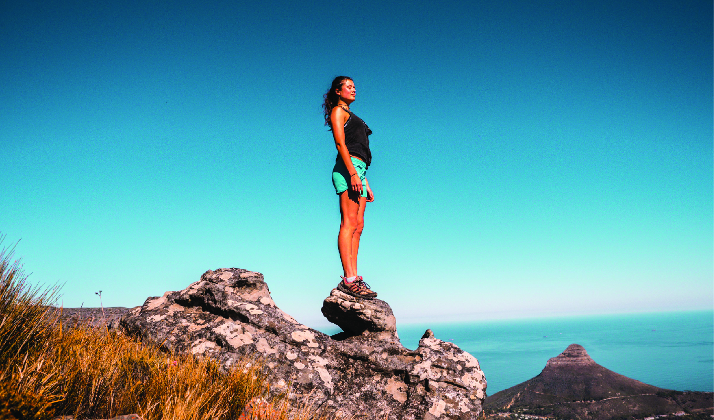 Woman in Black Top and Blue Shorts on Stone Under Blue Sky